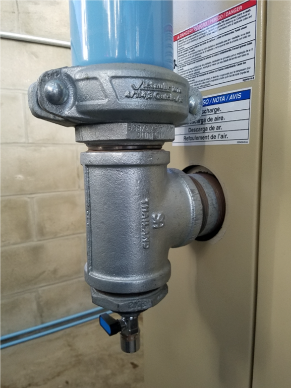 A close-up of a metal air compressor pressure regulator from Arle Compressors of Florida attached to a wall, featuring safety labels and warnings.